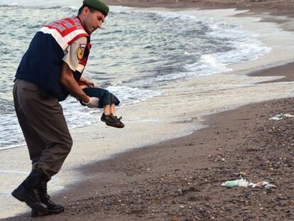 Un policía turco recoge el cadaver de un niño en una península de Turquía.