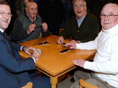 Rajoy, junto a tres jubilados jugando al dominó en el Hogar del Pensionista de Olmedo (Valladolid).