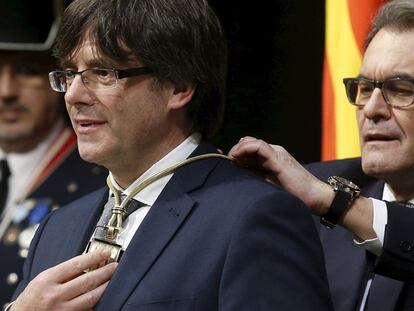 El nuevo presidente catalán, Carles Puigdemont, recibe la medalla de su predecesor, Artur Mas, durante la toma posesión.