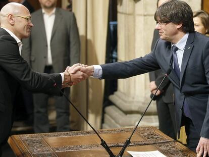 El consejero de Exteriores, Raül Romeva (i), saluda al presidente de la Generalitat, Carles Puigdemont, tras tomar posesión.