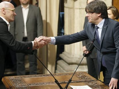 El consejero de Exteriores, Raül Romeva (i), saluda al presidente de la Generalitat, Carles Puigdemont, tras tomar posesión.