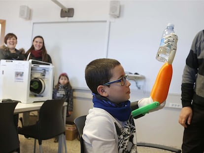 El niño Unai Blanco agarra un botellín de agua con su mano artificial realizada con una impresora 3D.