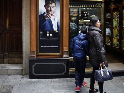 Un mendigo pide limosna al lado de una joyería, en Madrid.