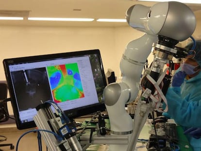 Dos de los creadores del robot supervisan cómo sutura tejido de intestino porcino.