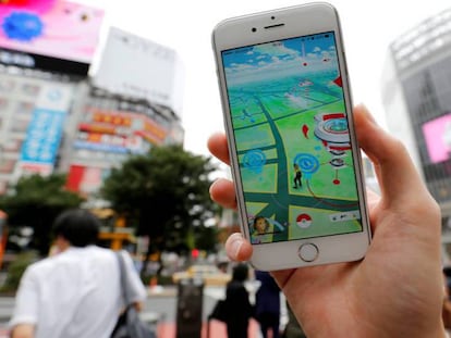 Un hombre juega a Pokémon Go con su móvil en una concurrida calle de Tokio.