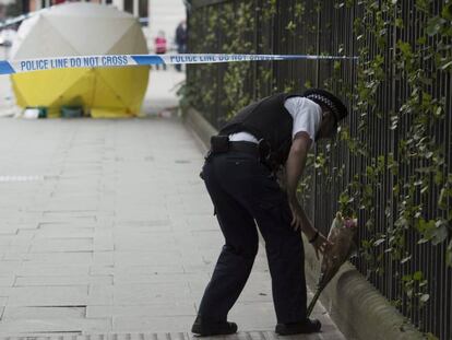 Un policía coloca flores en el lugar del ataque en Londres.
