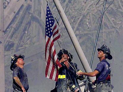 Varios bomberos izan una bandera de Estados Unidos sobre las ruinas de las Torres Gemelas, tras los atentados.