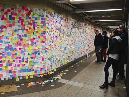 Algunos viajeros observan las notas que cubren un muro de la estación de metro de Union Square, en Nueva York.