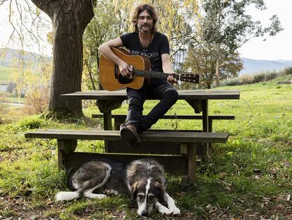 El músico toca la guitarra para su perra 'Dallas' en el jardín de su casa, en los Valles Pasiegos (Cantabria).