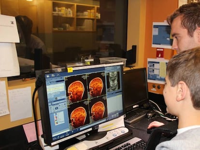 Uno de los investigadores enseña a un niño imágenes de su cerebro que acaban de ser tomadas por un escáner.