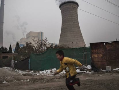 Un niño corre cerca de una central térmica de carbón en Pekín (China).