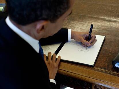 Barack Obama firma en su escritorio.