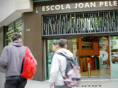 Tres alumnos pasan delante de la Escola Joan Pelegrí, uno de los colegios públicos cuyo director está a favor de abrir para el referéndum.