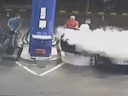 El gasolinero comienza a usar el extintor para apagar el cigarro.
