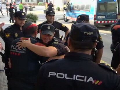 Un mosso se abraza a un policía nacional, rodeados de otros compañeros.