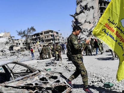 Un miembro de las Fuerzas Democráticas Sirias agita una bandera de su formación en Raqa (Siria).