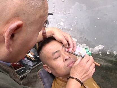 El barbero Xiong Gaowu afeita el interior del párpado a uno de sus clientes.
