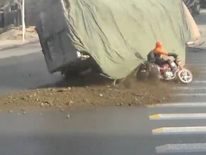 Un motorista se salva de ser aplastado por un camión y su carga en China
