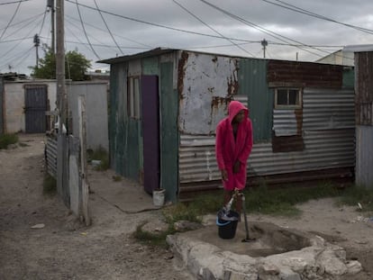 Mujer recoje agua en un asentamiento cerca de Ciudad del Cabo