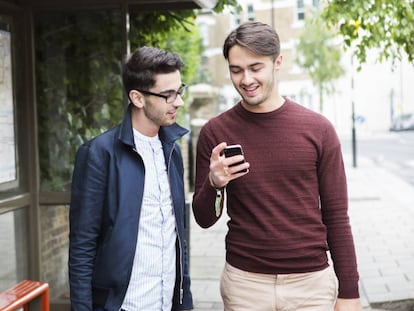 Dos hombres miran la pantalla de un móvil. En vídeo: Varios expertos analizan el caso de Grindr.