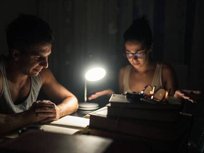 Dos jóvenes estudian en un ambiente oscuro.