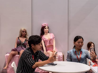 Dos expositores utilizan sus móviles junto a varias muñecas sexuales en la Asia Adult Expo, en Hong Kong.