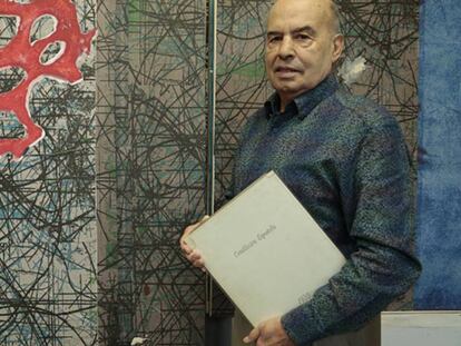 El artista José Luis Alexanco sostiene un ejemplar de la edición príncipe de la Constitución de 1978, en su estudio de Madrid.