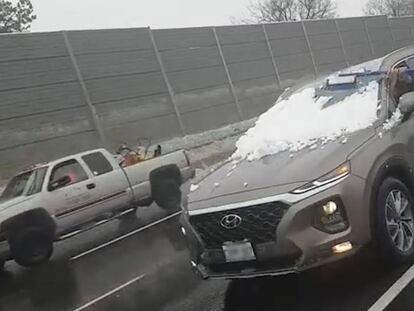 Una mujer quitando la nieve del parabrisas mientras conduce por una autopista en Toronto.