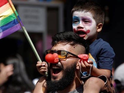 Foto: Un niño juega con la bandera arcoíris junto a su padre | Vídeo: Cómo ser padre en el resto de Europa