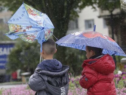Dos niños bajo la lluvia, esta mañana en San Sebastián.