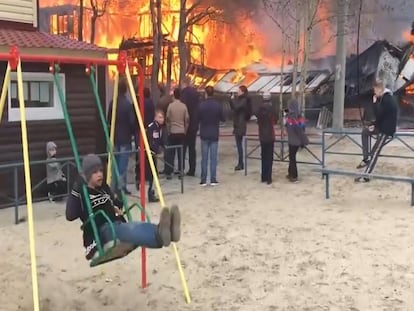 Niño se balancea en un columpio delante de un incendio.