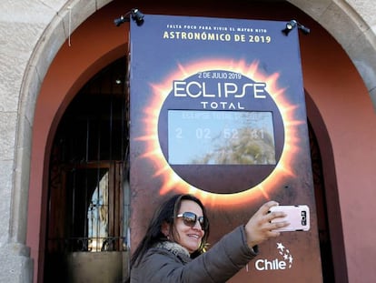 Una mujer se saca una selfie frente a un contador que informa las horas restantes para el eclipse de sol en Coquimbo (Chile).