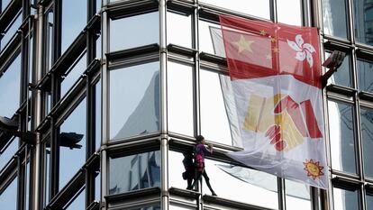 Alain Robert despliega una bandera por la paz en un rascacielos de Hong Kong. En vídeo, imágenes de la escalada y declaraciones del 'Spider-Man' francés.