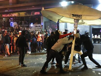 Un grupo de jóvenes rompe este sábado una sombrilla en el centro de Barcelona. En vídeo, las imágenes desde el furgón durante la noche del viernes.
