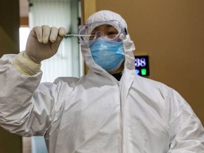 Un médico observa un termómetro en un hospital, en la zona de cuarentena de Wuhan, el pasado lunes. En vídeo, la OMS niega que haya una pandemia del coronavirus.