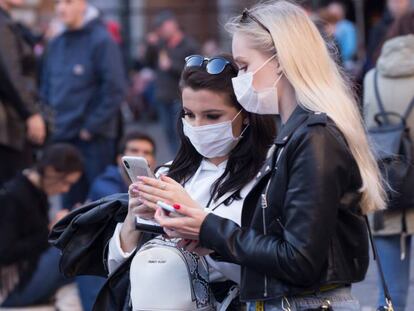 Dos mujeres consultan el móvil protegidas del coronavirus con mascarillas, en la plaza de la Rotonda (Roma). En vídeo, lo que se sabe del virus.