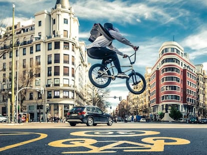 Un hombre tranquilo vuela sobre una bicicleta por las calles de Madrid