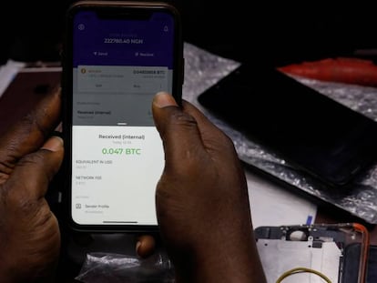 En el vídeo, la revolución bitcoin en África. En la imagen, Abolaji Odunjo, un vendedor de herramientas que comercia con bitcoin, demuestra cómo usa una aplicación de bitcoin en su teléfono móvil en su tienda de Lagos, Nigeria.