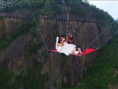 Una pareja china, colgada de un puente y dándose el "sí, quiero".