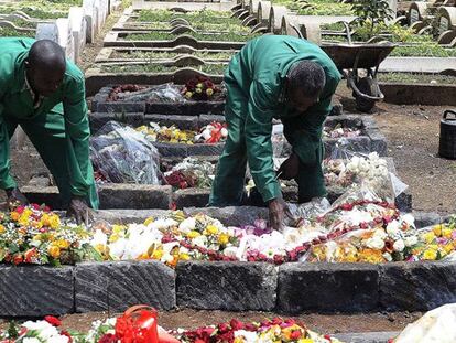 Dos operarios del cementerio depositan flores en la tumba de la periodista Ruhila Adatia-Sood, muerta en el ataque, durante su funeral.