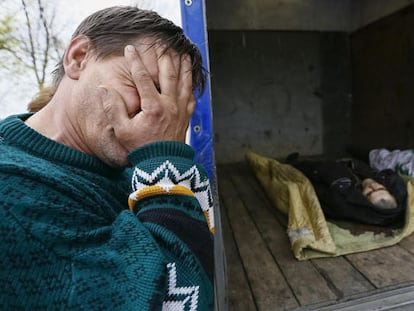 Um vizinho de Slaviansk chora diante de dois cadáveres depois do combate da madrugada do domingo em um posto de controle.