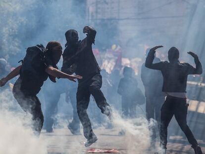 Manifestantes entre una nube de gas lacrimógeno