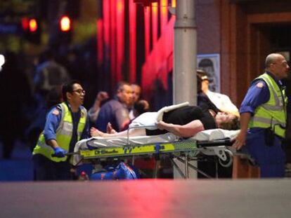Un herido es trasladado a la ambulancia tras el asalto al café Lindt.