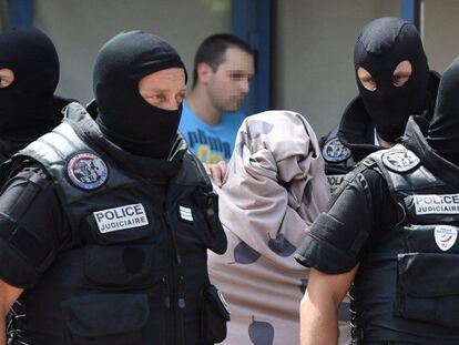 Policías custodian a una mujer tras registrar el piso de un sospechoso en Saint-Priest.