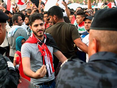 Un ciudadano iraquí entrega una flor de plástico a miembros de las fuerzas de seguridad en Bagdad, durante una manifestación contra la corrupción.