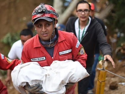 Um membro da equipe de resgate carrega o cadáver de uma criança.