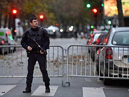 Un policía francés junto a la sala Bataclan, hoy domingo. En el vídeo, un detenido en Bélgica por su relación con los atentados.