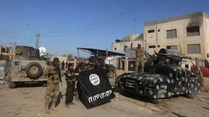 Fuerzas iraquíes muestran victoriosas una bandera del ISIS tras recuperar Ramadi.