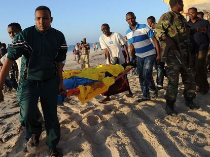 Varios hombres trasladan un cadáver de la playa.