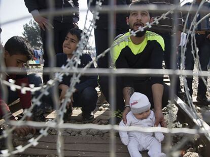 Pie de Foto: Un hombre espera junto a su hijo en la frontera griega con Macedonia, este martes.